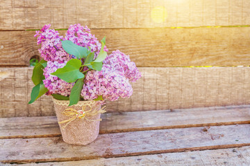 Ecology nature springtime concept. Bouquet of flowers beautiful smell violet purple lilac in vase on rustic wooden background. Inspirational natural floral spring blooming garden or park
