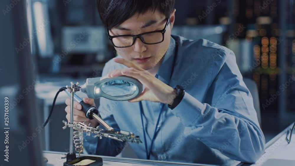 Poster close up of a professional japanese electronics development engineer in blue shirt soldering a circu