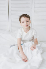 Fototapeta premium Cute boy woke up in the morning and sleepy sitting in bed