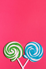 Fototapeta na wymiar Two striped lollipops on pink background