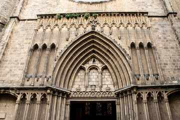 An entrance to the church as an element of gothic archetecture in Spain, Barcelona. Old ancient bas lica made of stone opened from outside