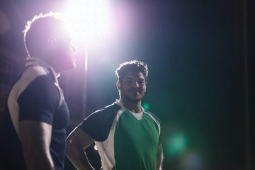 Sportsmen standing on rugby field under lights