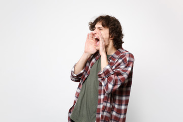 Portrait of young man in casual clothes looking aside screaming with hand gesture near mouth isolated on white wall background in studio. People sincere emotions lifestyle concept. Mock up copy space.