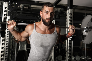 Naklejka premium Bodybuilding. Bearded man exercising at gym with barbell motivated close-up