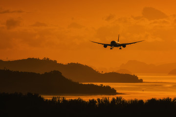 Fototapeta na wymiar Silhouette plane landing over island and sea