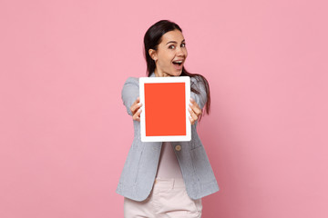 Portrait of excited young woman in striped jacket holding tablet pc computer with blank empty screen isolated on pink pastel background. People sincere emotions lifestyle concept. Mock up copy space.