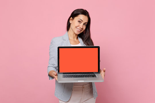 Portrait of stunning young woman in striped jacket hold laptop pc computer with blank empty screen isolated on pink pastel background. People sincere emotions, lifestyle concept. Mock up copy space.