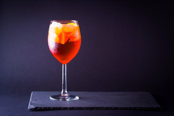 Cocktail aperol spritz on dark background. Summer alcohol cocktail with orange fruit in minimalism style. Italian cocktail aperol spritz on slate board. Copy space