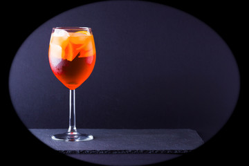 Cocktail aperol spritz on dark background. Summer alcohol cocktail with orange fruit in minimalism style. Italian cocktail aperol spritz on slate board. Copy space