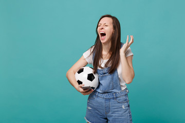 Displeased screaming woman football fan with soccer ball using mobile phone, spreading hands isolated on blue turquoise background. People emotions, sport family leisure concept. Mock up copy space.