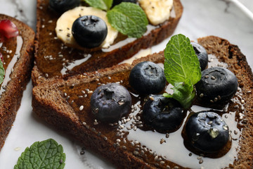 Tasty toast with blueberries, honey and chia seeds on plate, closeup