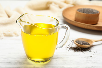 Glass jug with chia seed oil on table