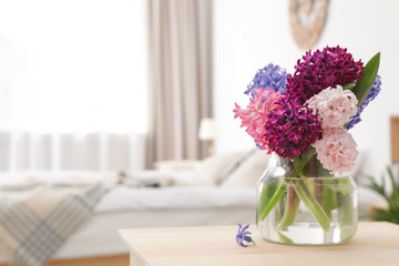 Beautiful hyacinths in glass vase on table indoors, space for text. Spring flowers