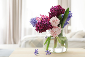 Beautiful hyacinths in glass vase on table indoors, space for text. Spring flowers