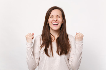 Portrait of laughing joyful pretty young woman in light clothes clenching fists like winner isolated on white wall background in studio. People sincere emotions, lifestyle concept. Mock up copy space.