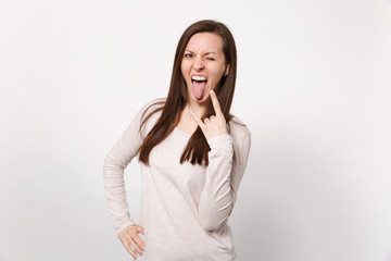 Crazy young woman in light clothes showing tongue, horns up gesture, depicting heavy metal rock...