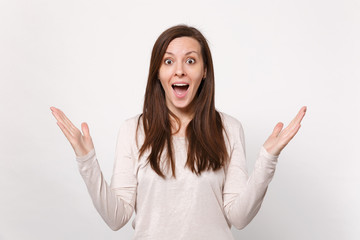 Portrait of surprised young woman in light clothes keeping mouth wide open, spreading hands isolated on white wall background in studio. People sincere emotions, lifestyle concept. Mock up copy space.