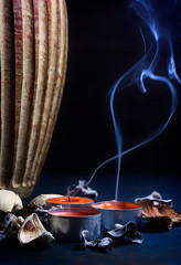 VELAS HUMEANTES CON FLORES SECAS Y JARRÓN DE FLORES SOBRE FONDO OSCURO