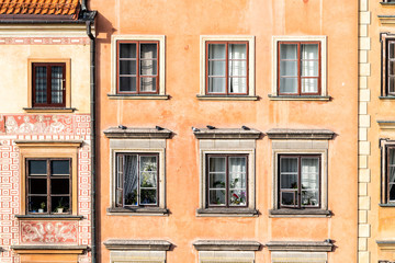 Fototapeta na wymiar Warsaw, Poland old town market square with closeup of historic street town architecture windows pattern of red orange yellow light color