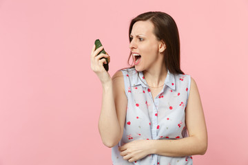 Irritated perplexed young girl in summer clothes hold looking on half of fresh ripe avocado fruit isolated on pink pastel background. People vivid lifestyle relax vacation concept. Mock up copy space.