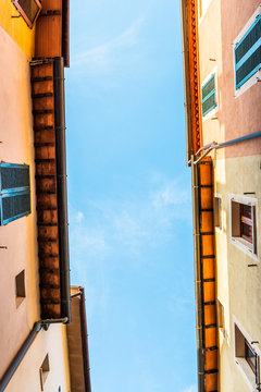 Chiusi, Italy street blue sky in small historic medieval town village in Tuscany looking up low angle vertical view during sunny summer day multicolored colorful painted walls