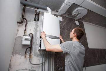 Installation and setting the new gas boiler for hot water and heating. Technician servicing the house heating system. - 257113508