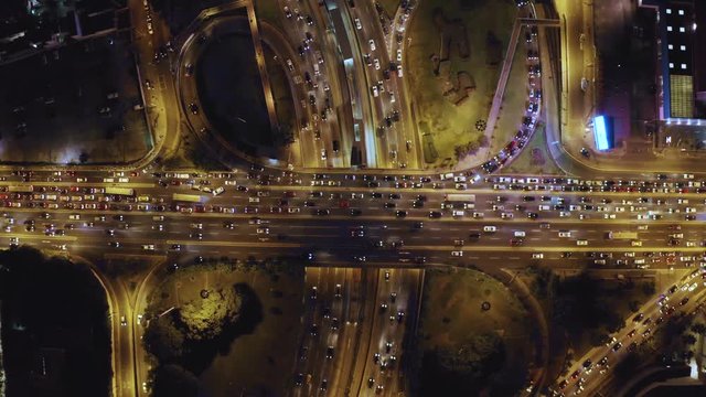 Aerial top view of cloverleaf  Interchange road at rush hour. Birds eye of city traffic at night time. City lights and cars stuck in Javier Prado and Via Expresa highways.