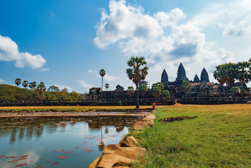Ancient ruins of Angkor Wat Temple are seen behind the pond with lilies, Siem Reap, Cambodia.