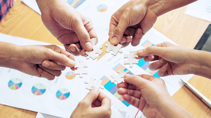 close up hand of group business partnership people puting together a jigsaw puzzle , business teamwork Strategy concept