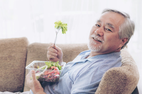 Lifestyle senior man feel happy enjoy eating diet food fresh salad on sofa