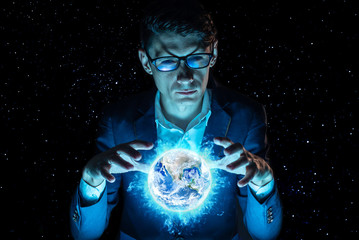 Man businessman holding hands over a blue glowing sphere in the form of planet earth. Elements furnished by NASA