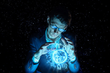 Fototapeta premium Businessman holding hands over the magic sphere with a horoscope to predict the future. Astrology as a business