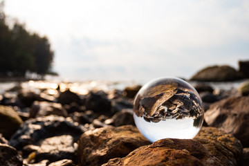 Crystal glass balls are displayed on a rocky coast with turquoise clouds covered with a summer background. Can be used for displaying or editing your background products Business travel