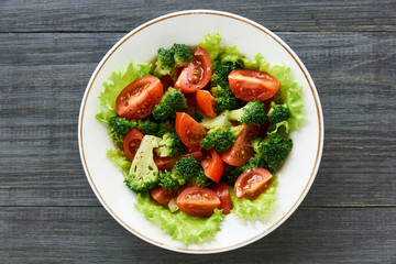 Salad with broccoli and cherry tomatoes in a white bowl