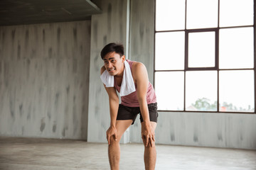 tired asian sport man take a break after high intensity workout in the gym