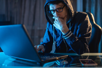 Male in the hood looking in the camera. Hacker attacks and stealing access databases with...