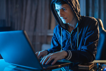 Hacker in the hood typing program code while stealing access databases with passwords. Cyber security concept