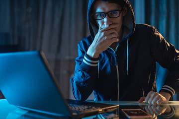 Hacker in glasses thinking about the problem of hacking and stealing access databases with...
