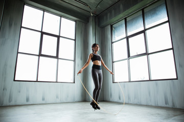 Fototapeta na wymiar portrait of asian sport young woman jumping rope in the gym