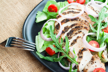 Close up organic vegetables salad with grilled chicken on black plate. Healthy food. Beauty concept