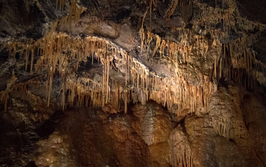 Stalactites line the wall and ceiling of a cave in the Peak District, England.