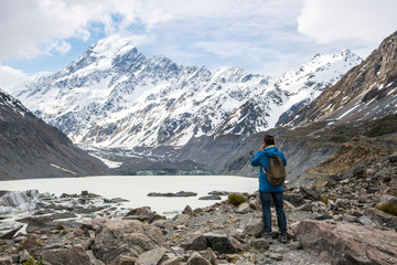 Tourist standing and looking to the beautiful view of Hooker glacier lake and Mount Cook (3,764...