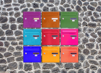 Boîtes aux lettres couleurs incrustées dans un mur de pierres