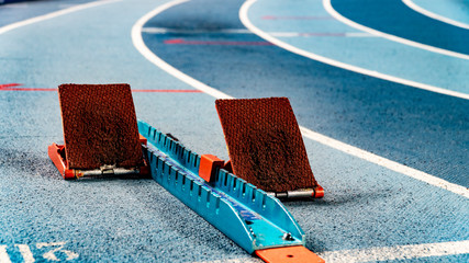 Athletics starting blocks on race blue track - obrazy, fototapety, plakaty