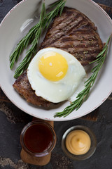 Plate with bbq beef schnitzels and fried egg, vertical shot, closeup, above view