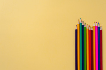Flat lay - Bright colorful pencils on yellow background