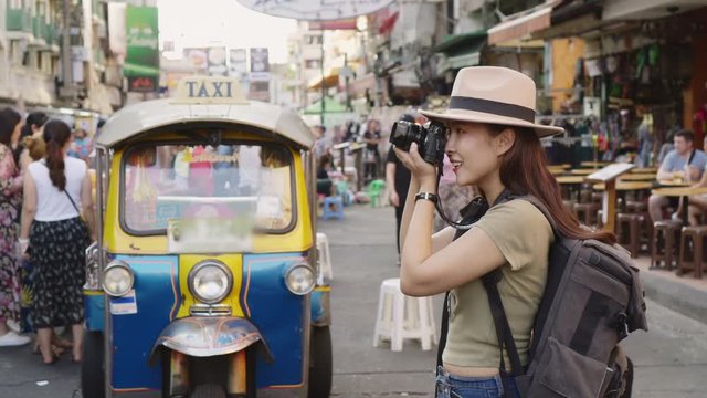 Asian traveler/tourist walking and travelling taking photo in Khao San rd. walk street, Bangkok, Thailand