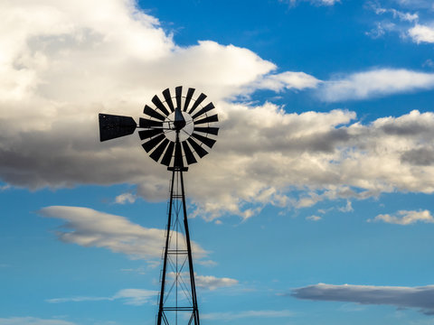 Windmill in Silhouette on a Blue and Cloudy Sky