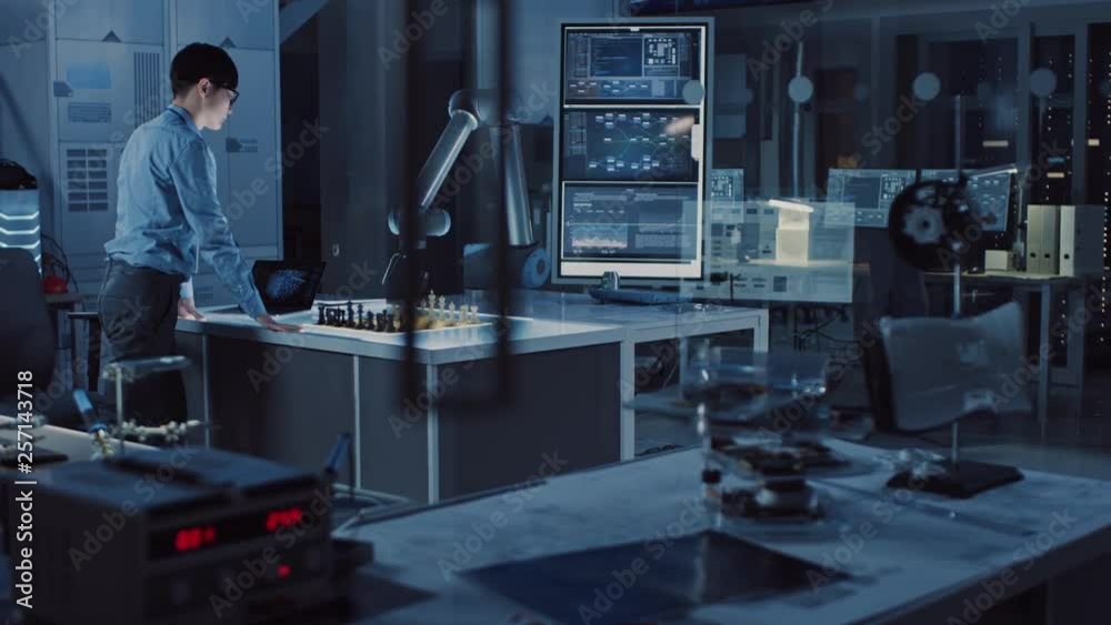 Poster Professional Japanese Development Engineer is Testing an Artificial Intelligence Interface by Playing Chess with a Futuristic Robotic Arm. They are in a High Tech Modern Research Laboratory.