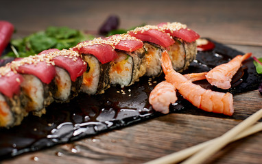 Close up of tasty fresh sushi rolls with fish, rice and shrimps on black slate. Sushi rolls served on a wooden table in a restaurant